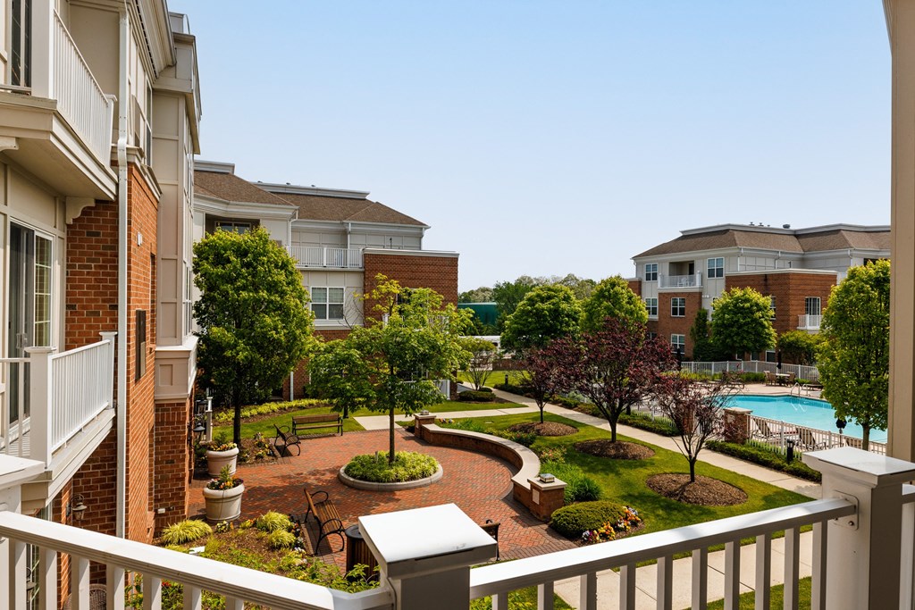 A view of a courtyard from a balcony with a pool in the background.