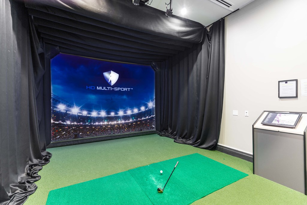 A golf simulator room with a screen showing a stadium and the words "HD Multi-Sport".