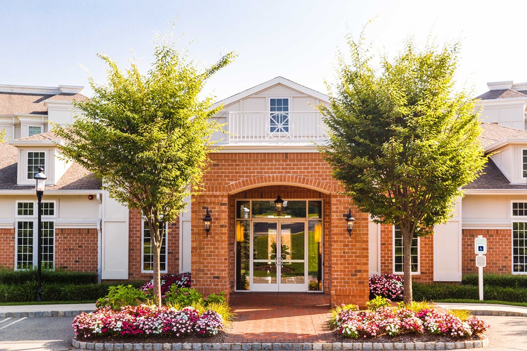 the front of a building with trees and flowers in front of it