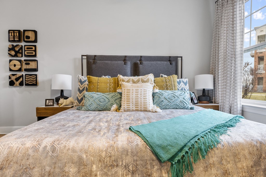 A bed with a gold comforter and a green throw.