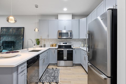 an open kitchen with stainless steel appliances and white cabinets