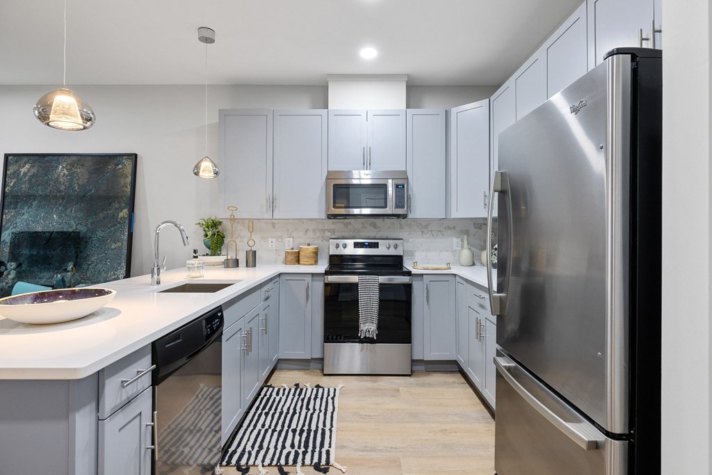 an open kitchen with stainless steel appliances and white cabinets