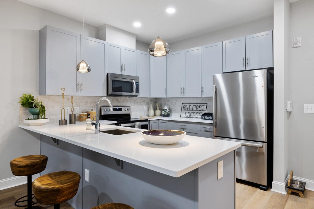 A modern kitchen with a white countertop and a stainless steel refrigerator.