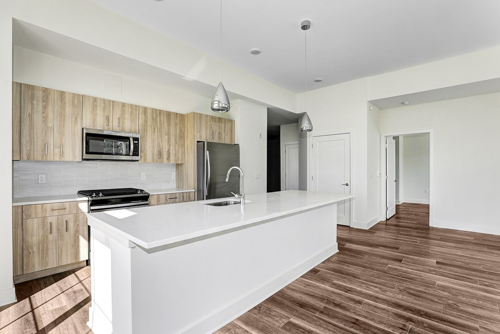A modern kitchen with a white countertop and wooden cabinets.