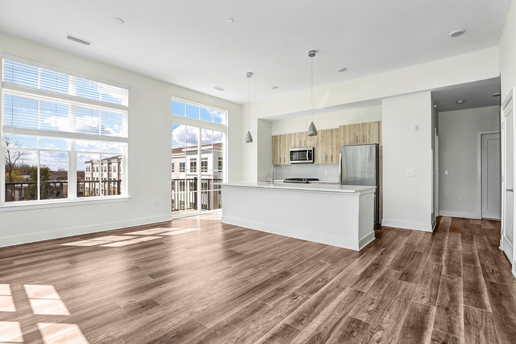 A spacious kitchen with wooden flooring and a large window.