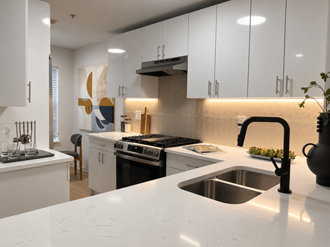 A modern kitchen with a stove, sink, and cabinets.