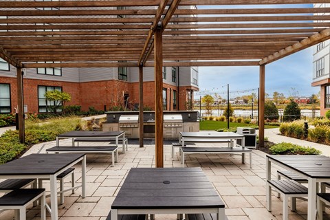 A wooden pergola over a patio with benches and tables.