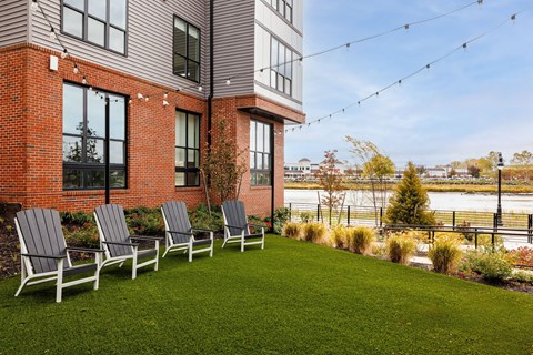 Four chairs are lined up on a lawn in front of a building.
