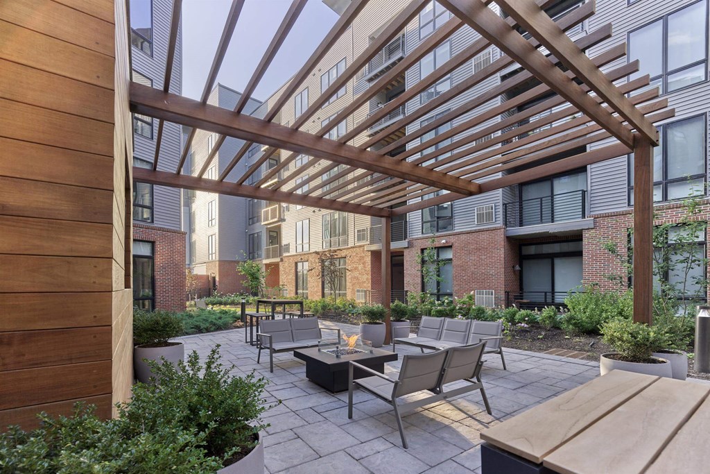 A wooden pergola over a patio with chairs and tables.