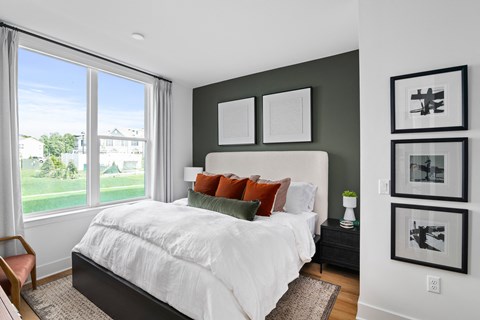 A bedroom with a large bed and a view of a green lawn outside the window.
