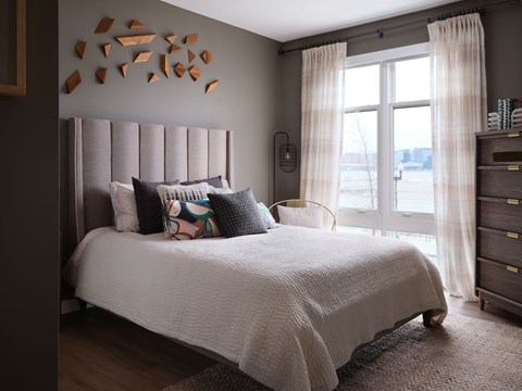 A bedroom with a large bed and a window with curtains.