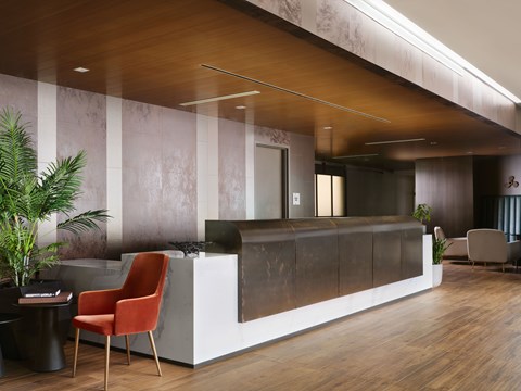 A modern office lobby with a wooden floor and a reception desk.