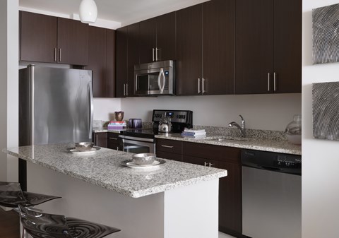 A modern kitchen with a stainless steel refrigerator and a granite countertop.