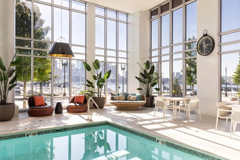 A large indoor swimming pool with a sunny view outside.
