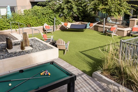 A pool table is surrounded by a grassy area and a patio.