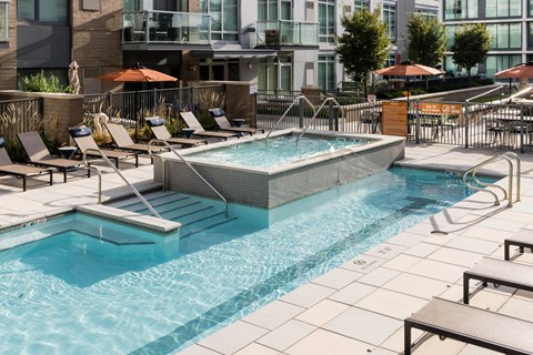A swimming pool surrounded by lounge chairs and umbrellas.