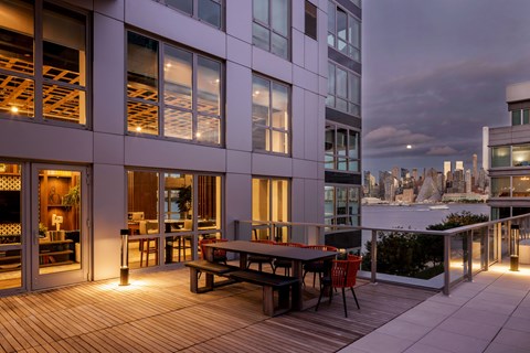A modern building with a wooden deck and a table set for two.