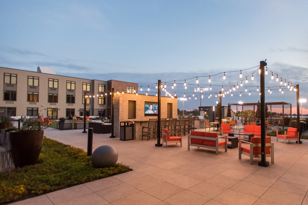 a rooftop patio at dusk with tables and chairs and a tv