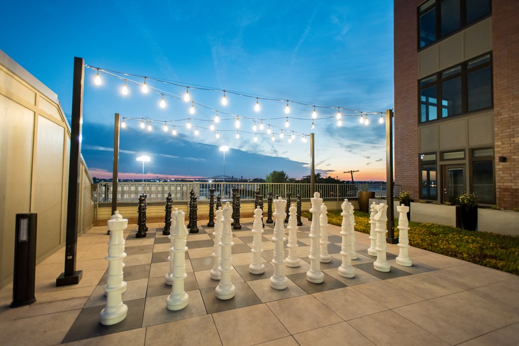 a large chess board in front of a building with lights on it