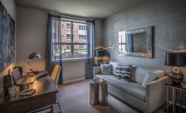 a living room with a couch and a desk and a window