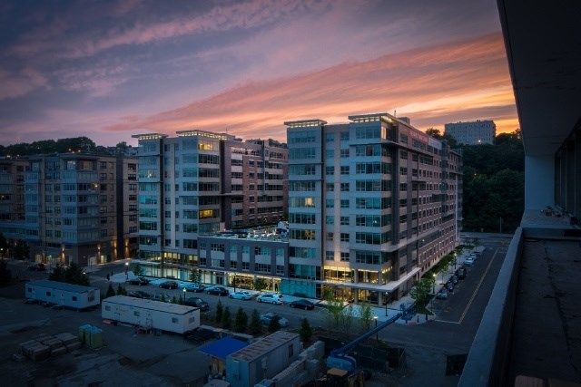 A modern apartment complex is bathed in the warm glow of evening lights.