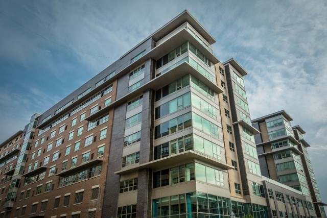 A modern multi-story building with a mix of brown and beige balconies.
