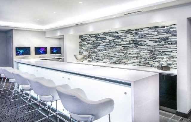 a white bar with white chairs and a stone wall