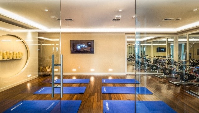 a gym with blue yoga mats on the floor and mirrored walls