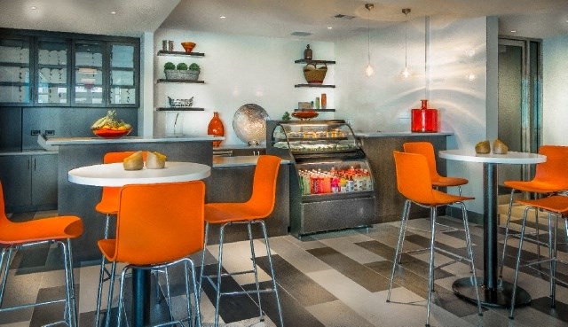 a small restaurant with orange chairs and tables and a grill