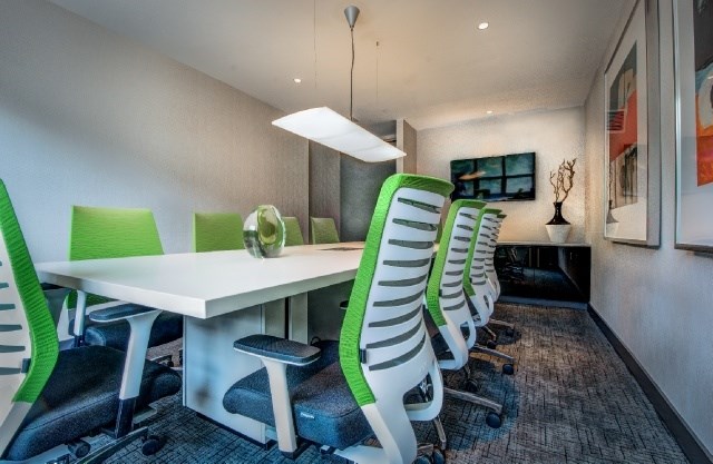A conference room with a long table and green chairs.