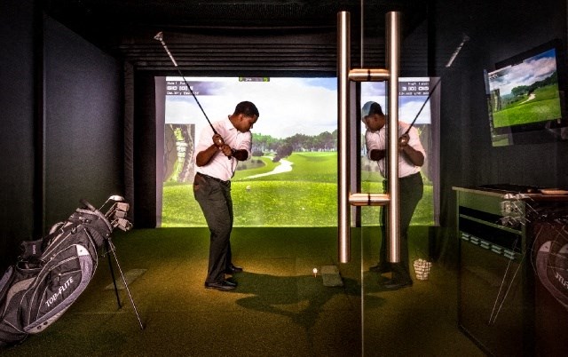 a man holding a golf club in a golf simulator