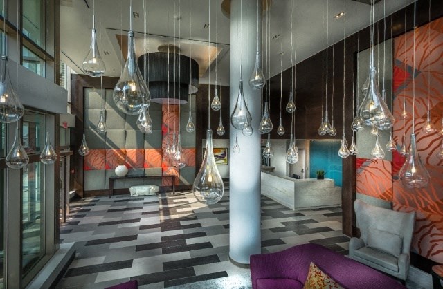 a lobby with lights and chairs and a man in a suit in the background