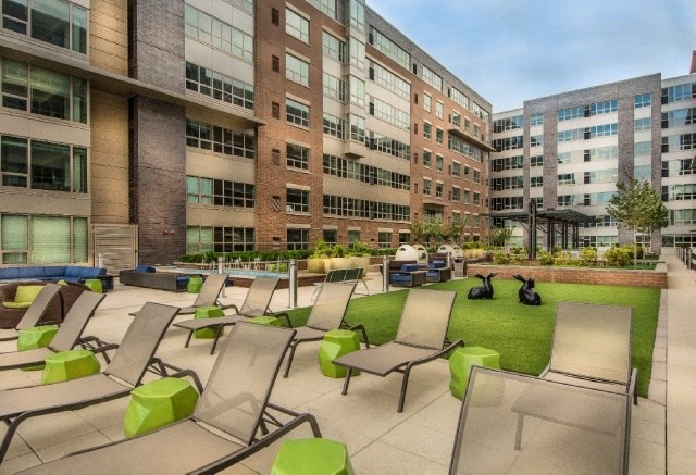 an outdoor lounge area with lounge chairs in front of an apartment building