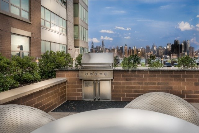 A view of a city skyline from a rooftop with a stainless steel structure in the foreground.
