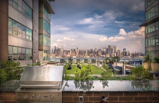 a view of the city skyline from a rooftop patio with a grill