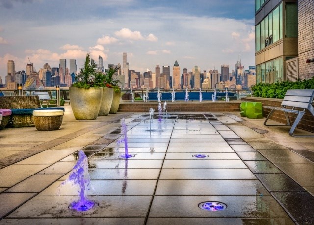 A cityscape is visible in the background of a rooftop patio with a fountain.
