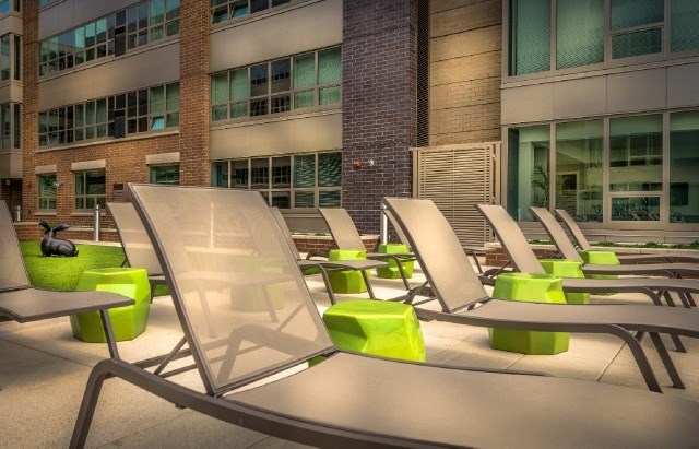 A row of green and silver chairs are lined up on a patio.