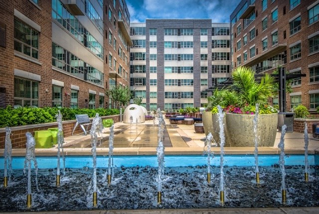 a fountain in front of a swimming pool in an apartment building