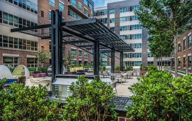 A modern outdoor seating area with a black metal pergola and a mix of seating options.