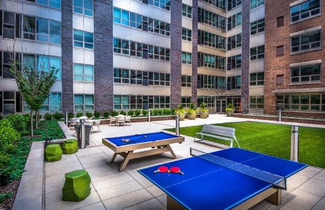 two ping pong tables in front of an office building with picnic tables and benches
