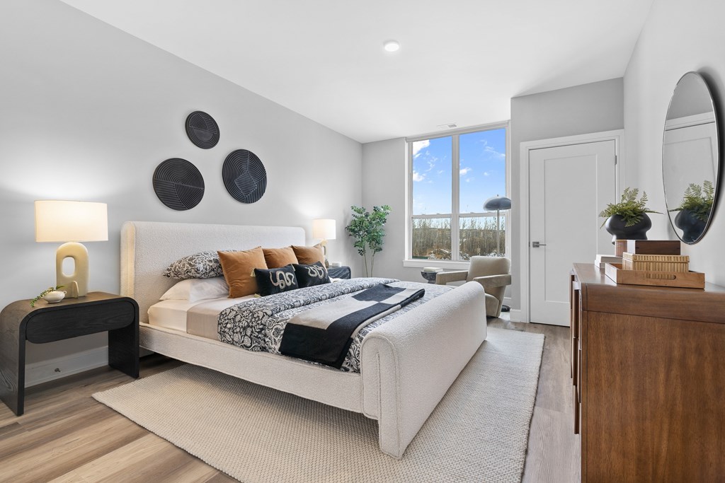 A bedroom with a large bed, a nightstand, and a mirror.