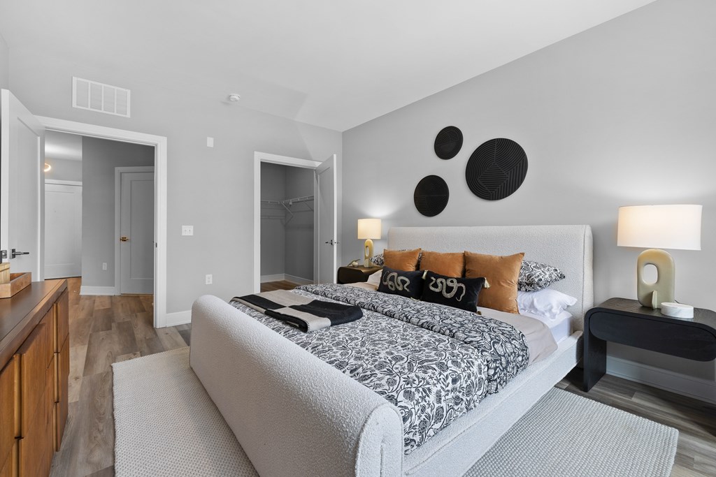 A bedroom with a large bed and a nightstand with a lamp.