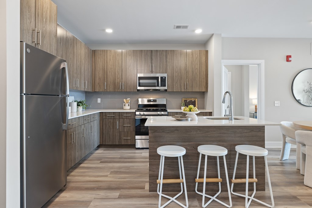 A modern kitchen with a refrigerator, stove, and bar stools.