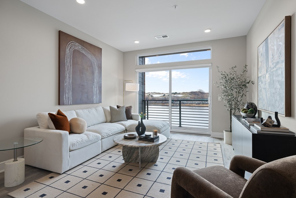 A living room with a white couch, a glass coffee table, and a large painting on the wall.
