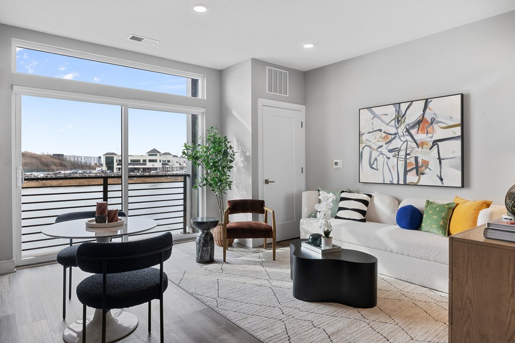 A living room with a couch, chairs, and a large painting on the wall.
