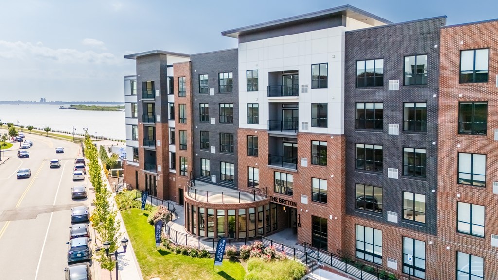 A modern apartment complex with a parking lot in front.