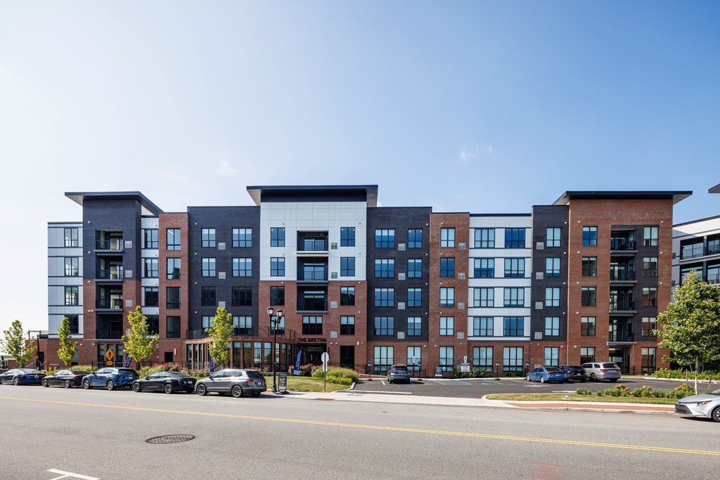 A large apartment building with a parking lot in front.