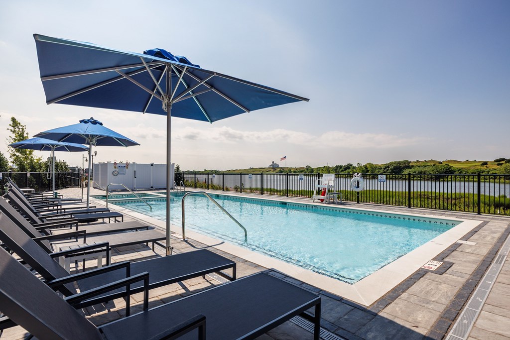 A pool with sun loungers and umbrellas.