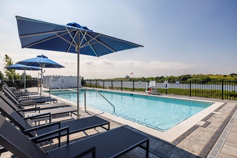 A pool with sun loungers and umbrellas.