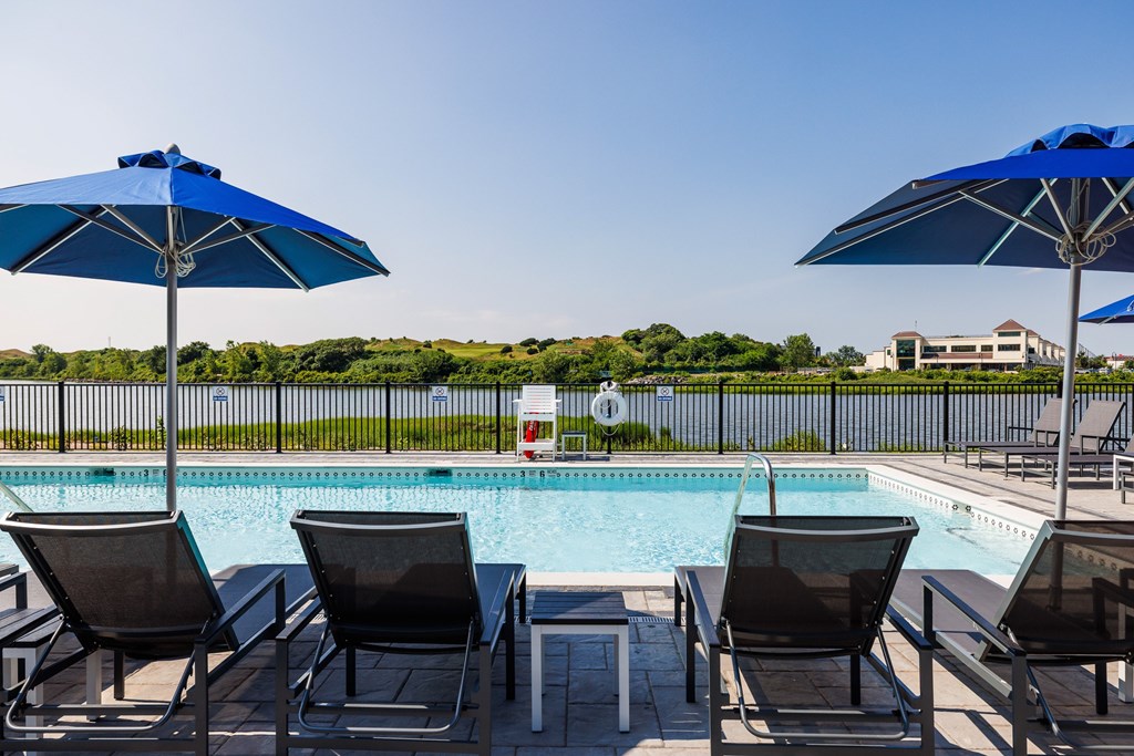 A poolside setting with chairs and umbrellas.